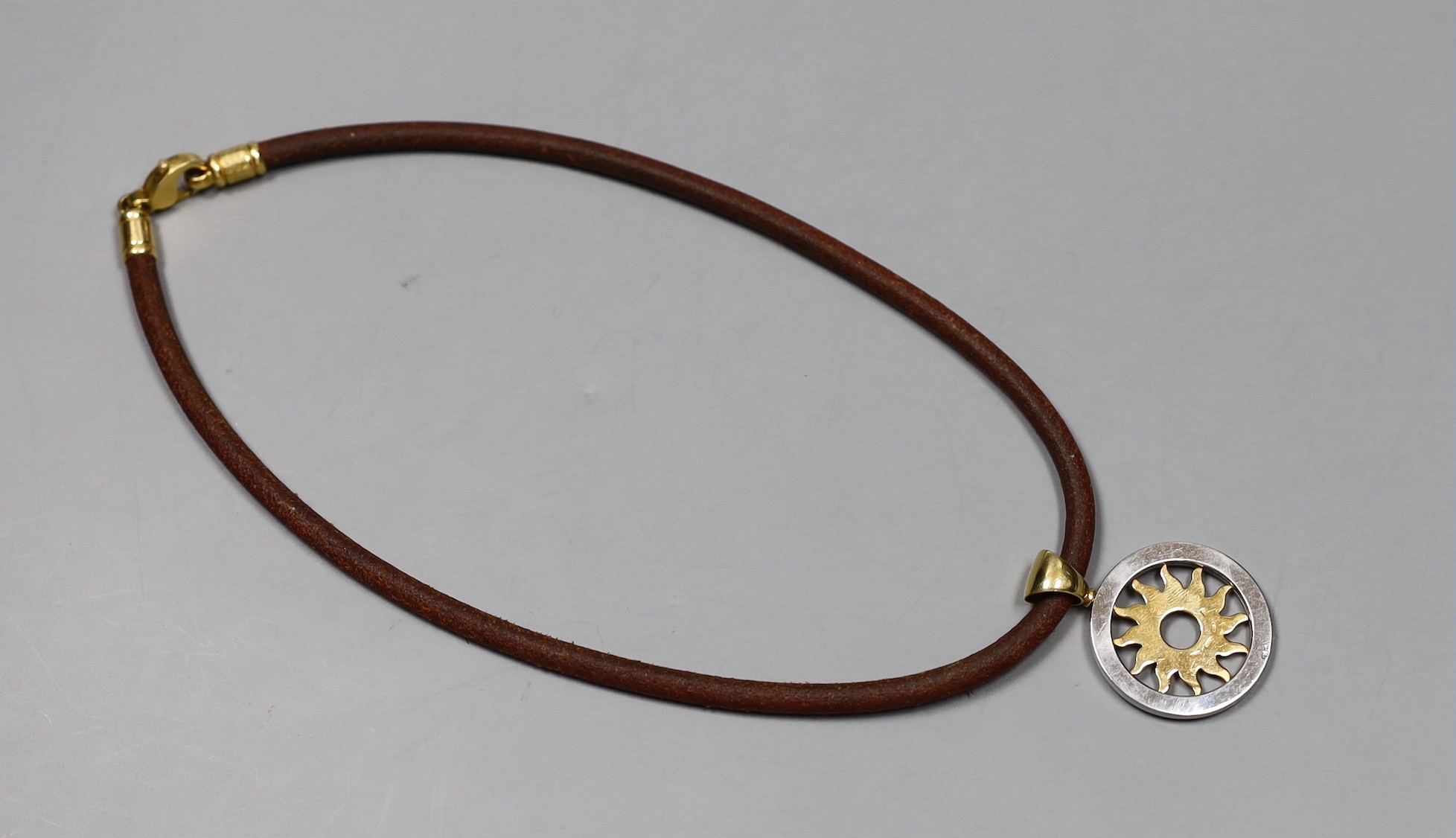 A modern Bulgari 18k and steel circular 'sun' pendant, 30mm, on a Bulgari fabric necklet, with 750 clasp, gross weight 27.4 grams.
